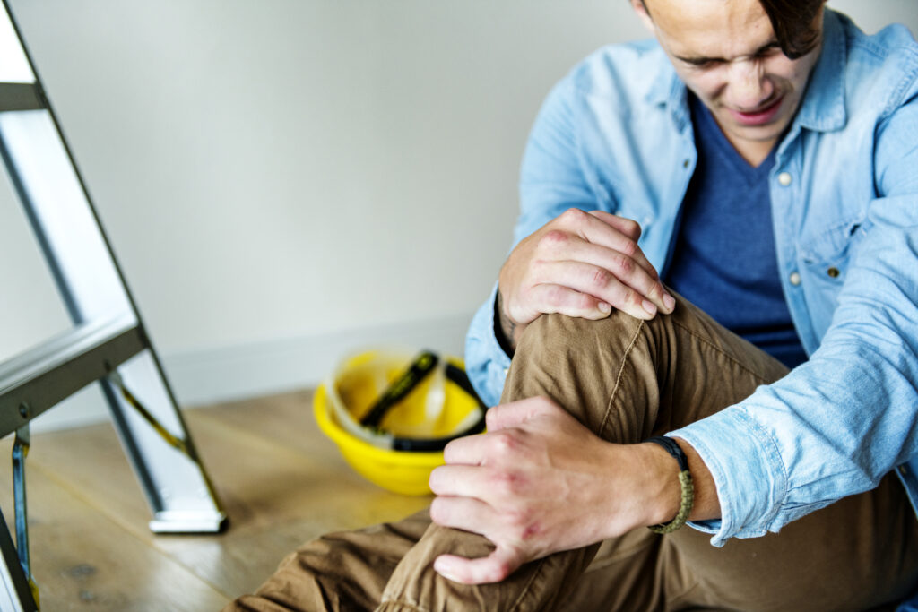 Construction worker holding his knee in pain due to an injury that happened at work
