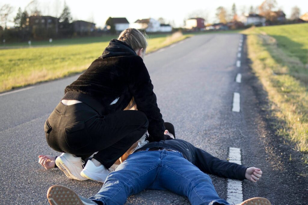 Woman finding an unconscious person on the road and is caring for him